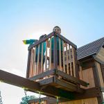 Backyard Discovery Skyfort All Cedar Swing Set, Elevated Covered Wood Roof Clubhouse with Bay Windows, 2 Belt Swings, Web Swing, 10ft Wave Slide, 5 ft Tube Slide, Covered Picnic Table, 5 ft Rock Wall from Backyard Discovery